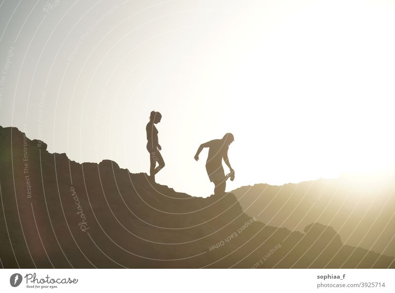 silhouette of couple walking downhill in backlight during sunset mountain vacation adventure hiking together summer sunrise woman climbing active walking home