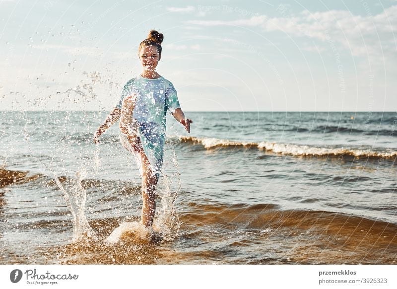 Girl splashing a water towards camera enjoying a free time over sea on a beach at sunset excited positive emotion carefree nature outdoors travel happiness