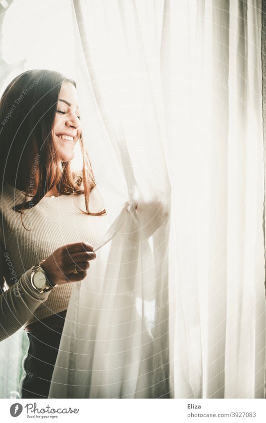 Smiling woman stands at the window in the backlight and plays with the curtain Woman smilingly Back-light Window Drape Joy Laughter Good mood Sun sunny Bright