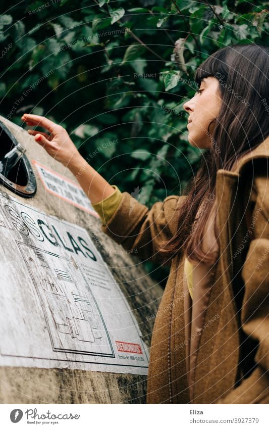 A young woman disposes of a bottle in a bottle bank. Recycling. Glass for recycling Container bottles Glass waste Trash Trash container waste separation