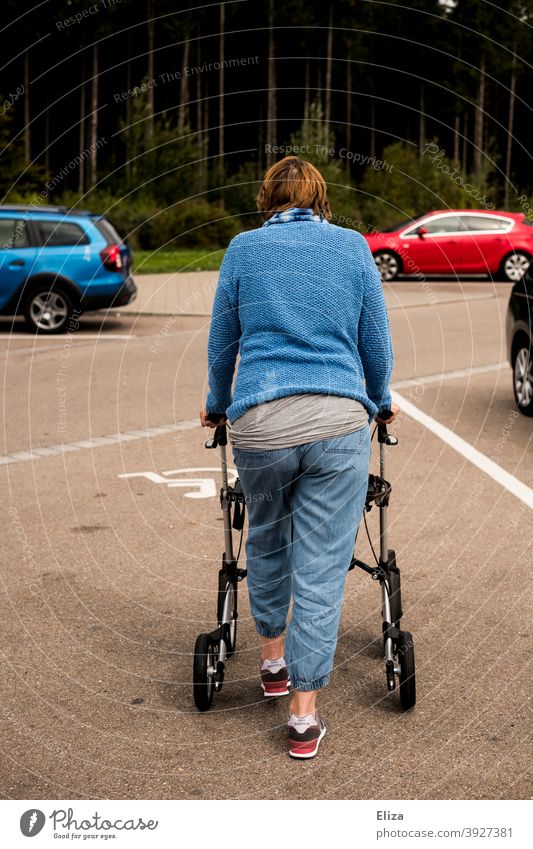 A woman with a walking disability pushes her walker across a disabled parking space walking impediment handicap Woman Human being Rollator Handicapped Mobility