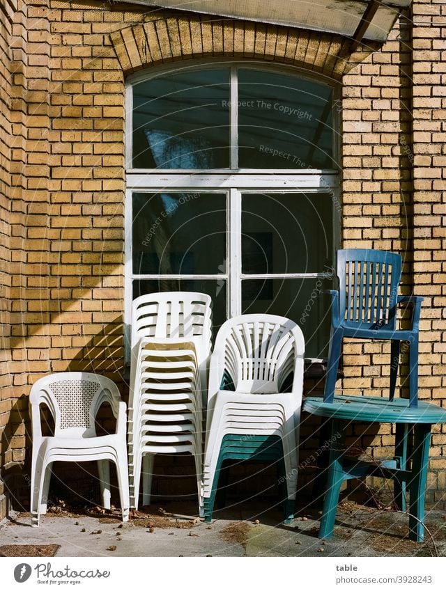 several stacking chairs made of plastic are stacked on top of each other against a house wall Chair Stack Sunlight Exterior shot Colour photo Arrangement