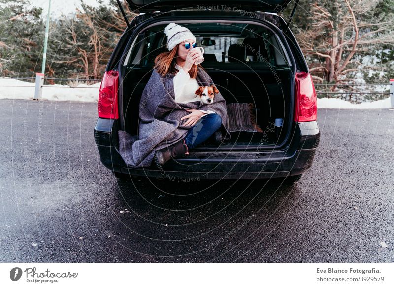 young woman and cute jack russel dog in car. Winter season, snowy mountain background blanket nature together wanderlust beauty active togetherness friends day