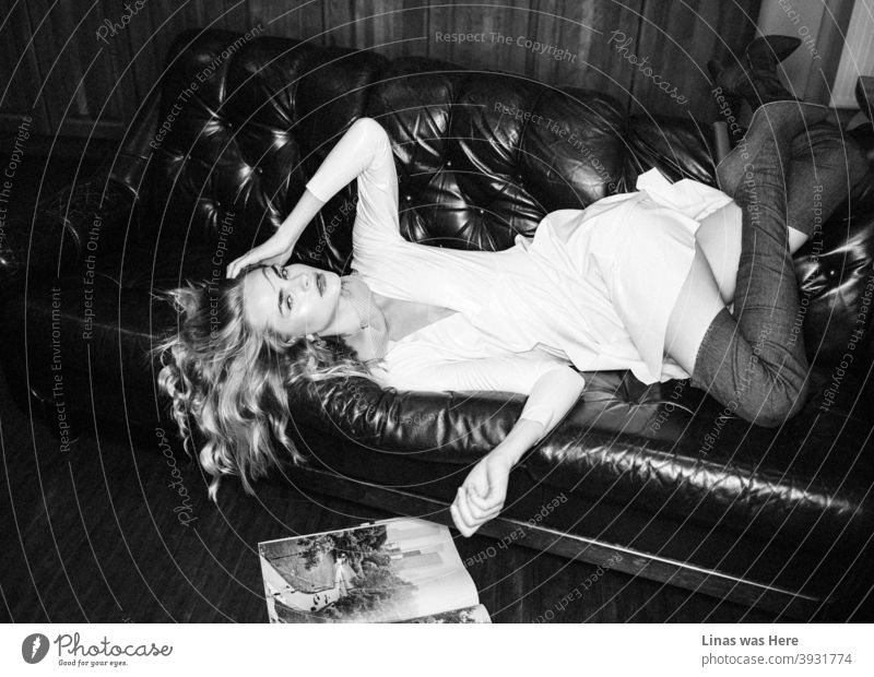 A fashion shoot with a gorgeous female model dressed in a white latex dress. With her high heels, she is falling down the couch. Some magazines are on the floor. This beautiful girl knows how to pose.