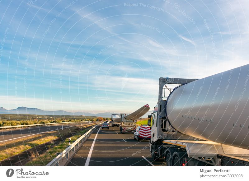 Special transport of wind turbine blades. Several trucks with wind turbine blades circulating on the highway with beacon vehicles behind to warn other road users of the danger.