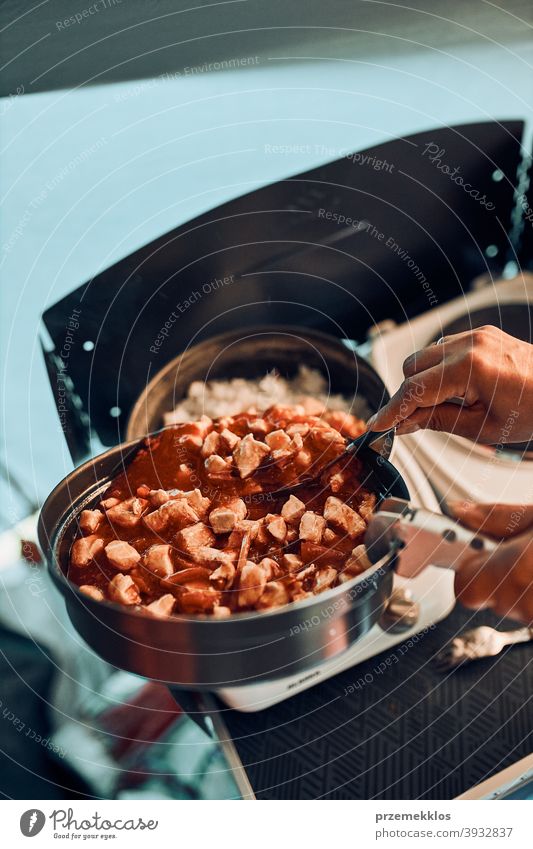 Close up of female hands putting dish with tomato sauce. Woman cooking meal on electric stove on camping during summer vacations cooker cuisine dinner eating