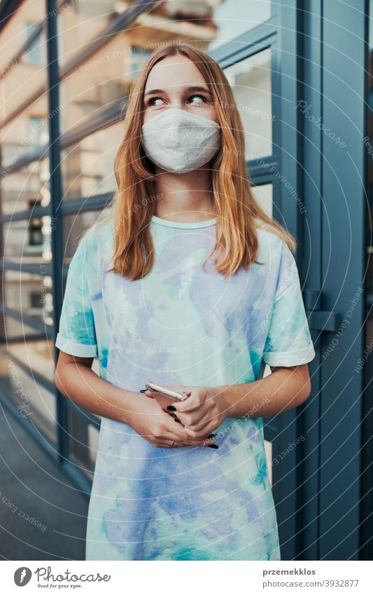 Portrait of young woman girl standing at store front downtown wearing face mask to avoid virus infection caucasian cellphone conversation covid-19 female