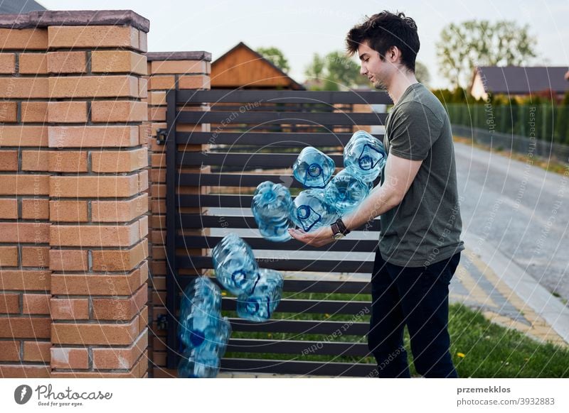 Young man throwing out empty used plastic water bottles into trash bin blue collect collecting container crushed disposal ecology environment female garbage