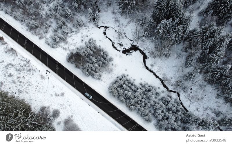 Aerial view with a drone of a road with a car driving through the forest in the winter time Aerial photograph drone photo Winter Street Driving Snow Forest