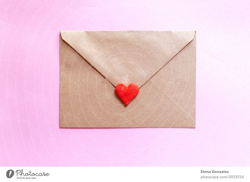 Love letter in a craft envelope with clay red heart on pink background. craft paper symbols mail elements ideas relationship details lover send address