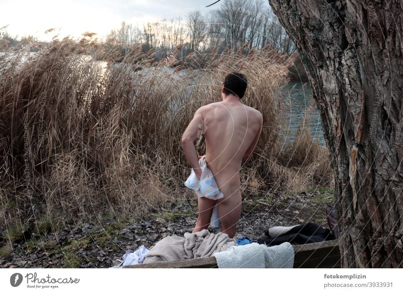 Back view of a naked young man drying himself after a cold winter bath Ice Swimming naked man Ice bathing Harden hardening Strengthen the immune system