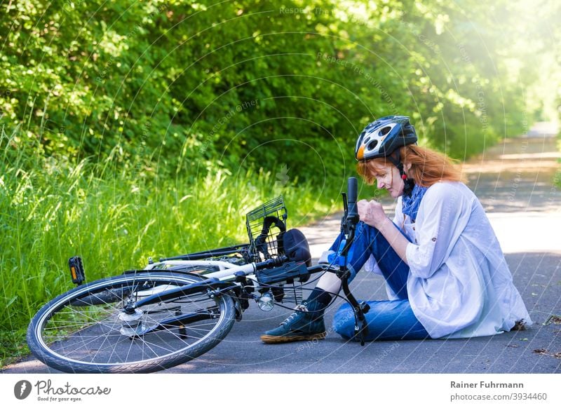 a woman had an accident, she fell with a bicycle and hurt herself Accident Bicycle bicycle accident Sudden fall violation cyclist Helmet Knee Street off Summer