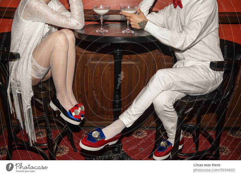 It’s a date and these two young people are flirting all over the table. Dressed in white with avant-garde shoes all shining from far away they’re having glasses of milk. The red carpet represents this fancy restaurant as a perfect place for flirting.