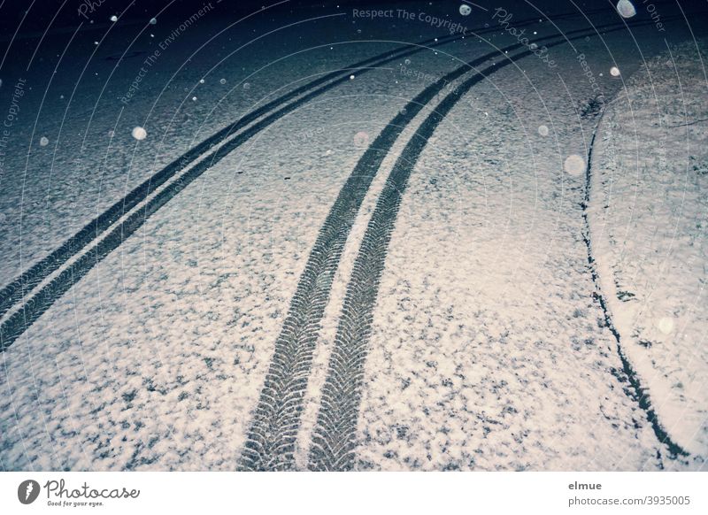 tire tracks of a car running in an arc on a lightly snow-covered road in the nocturnal flake swirl / winter / slippery roads Car track Winter Snow