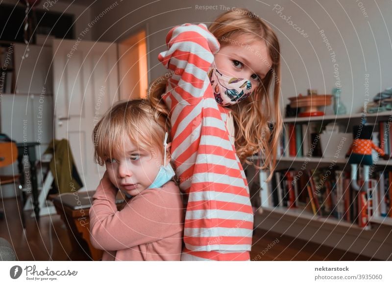 Sibling Sisters Posing Back to Back cloth mask child sisters kid children female girl Indoor home at home siblings back to back caucasian face mask protective