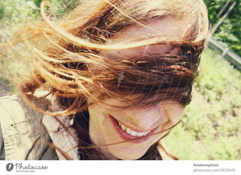 Portrait of a smiling woman with flying hair in front of her eyes Face windy Identity Looking Woman portrait Long-haired naturally hairstyle take a walk out