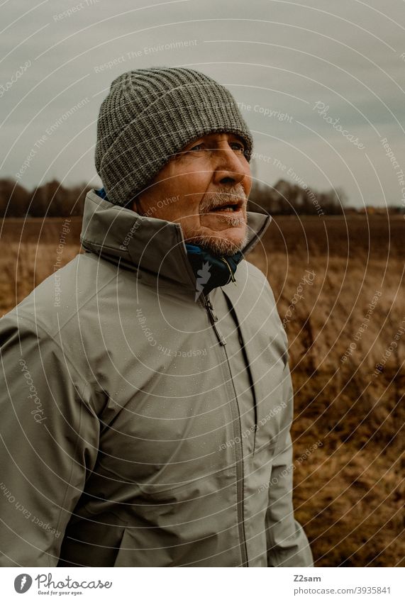 Portrait eines sportlichen Rentners in der Natur spazieren natur outtdoor rentner alter mann portrait mütze winter kälte landschaft wald sträucher freizeit