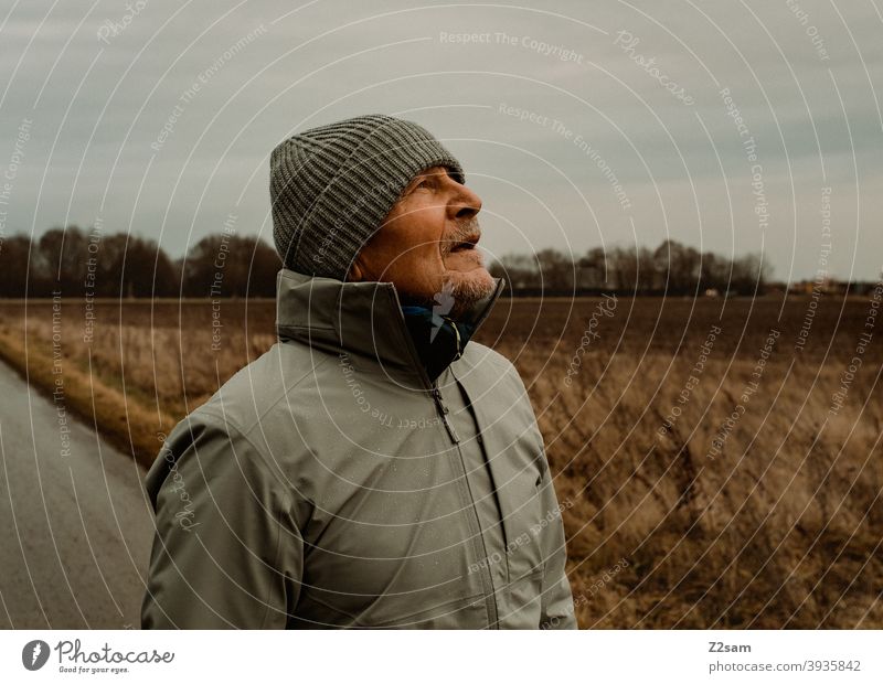 Sportlichen Rentner mit Blick nach oben in der Natur spazieren natur outtdoor sport sportlich rentner alter mann portrait mütze winter kälte landschaft wald