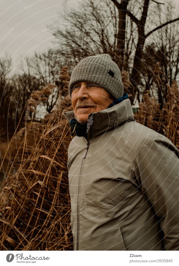 Portrait eines sportlichen Rentners in der Natur spazieren natur outtdoor rentner alter mann portrait mütze winter kälte landschaft wald sträucher freizeit