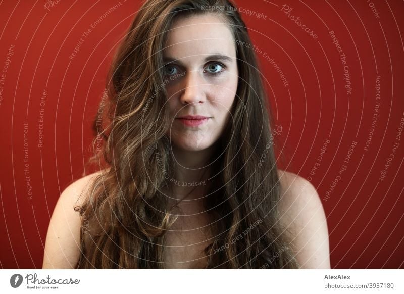 Portrait of a young woman with big green eyes in front of a red wall Young woman Central perspective Expectation Day Intensive Wall (building) Red salubriously