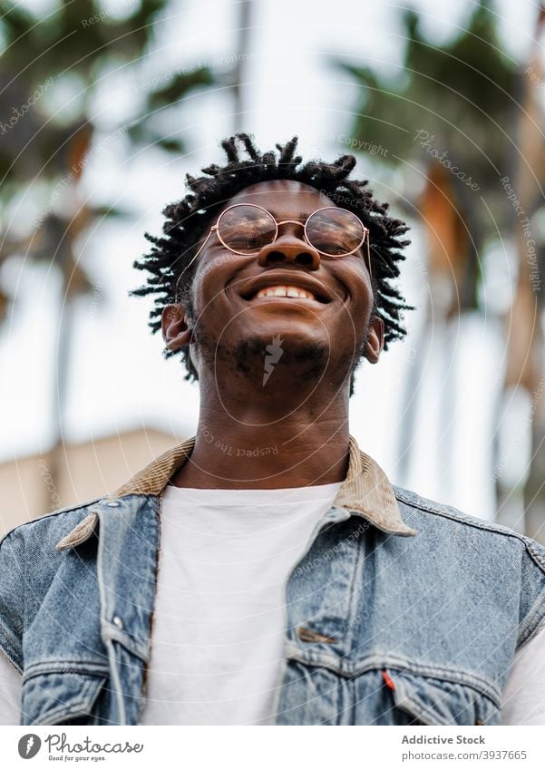 Optimistic black man in trendy outfit and eyeglasses cheerful optimist happy afro dreadlocks style young charismatic male african american ethnic denim content