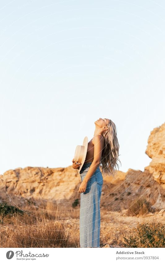 Naked woman covering breast with hat in nature slim topless tranquil enjoy sunset style female jeans relax harmony stand summer naked serene calm evening young