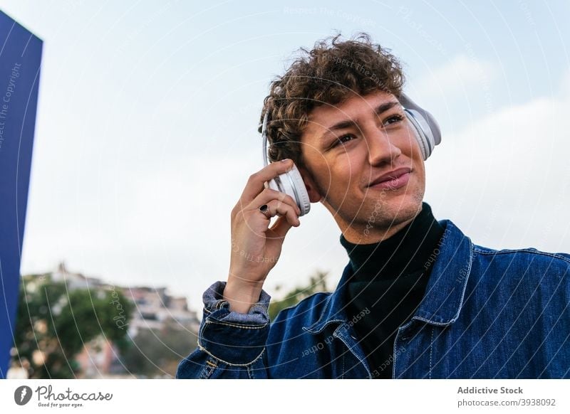 Cheerful man listening to music in headphones city enjoy song wireless young smile male relax curly hair cheerful delight audio happy sound gadget guy melody