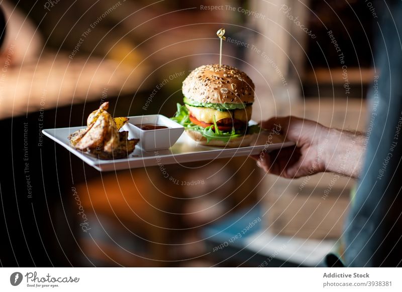 Waiter serving hamburger and potatoes in cafe serve fast food meal restaurant tasty lunch dinner service waiter sauce cuisine yummy dish order gastronomy