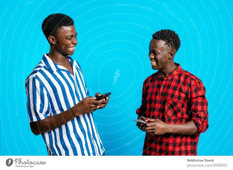 Positive black men laughing together in studio best friend having fun friendship browsing smartphone positive male ethnic african american trendy cheerful