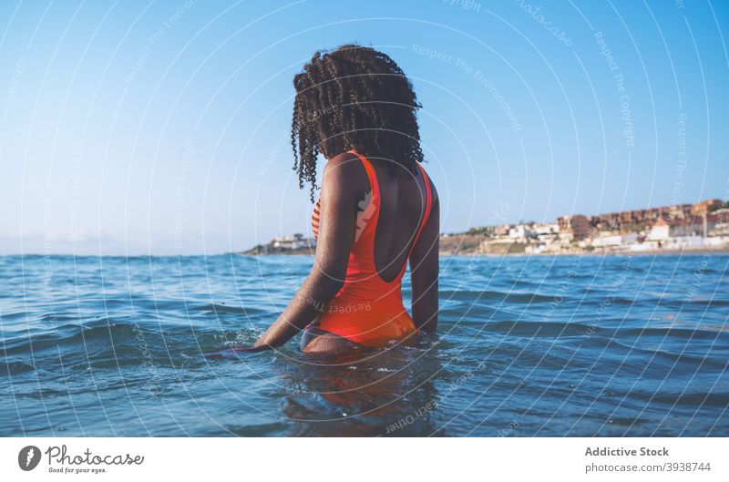 Anonymous black fit woman relaxing in rippling sea on sunny day swim vacation style tourist recreation summer resort holiday seaside female young