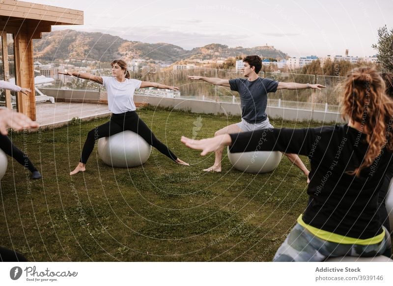 Group of people doing pilates exercises on fit balls group class training side bend together stretch lawn sportswear company wellness wellbeing fitness healthy