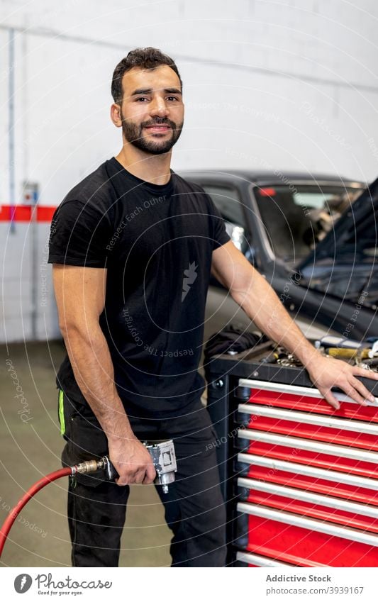 Busy mechanic with tool cabinet in car workshop man technician service instrument station male job garage maintenance repair glove handyman auto occupation