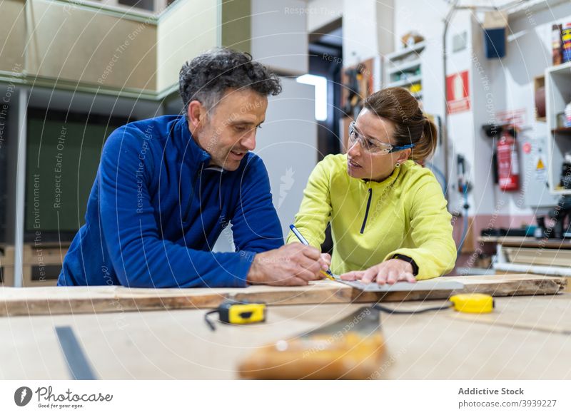 Focused colleagues measuring wood in modern workshop measure woodwork together concentrate master joinery occupation professional coworker man woman adult