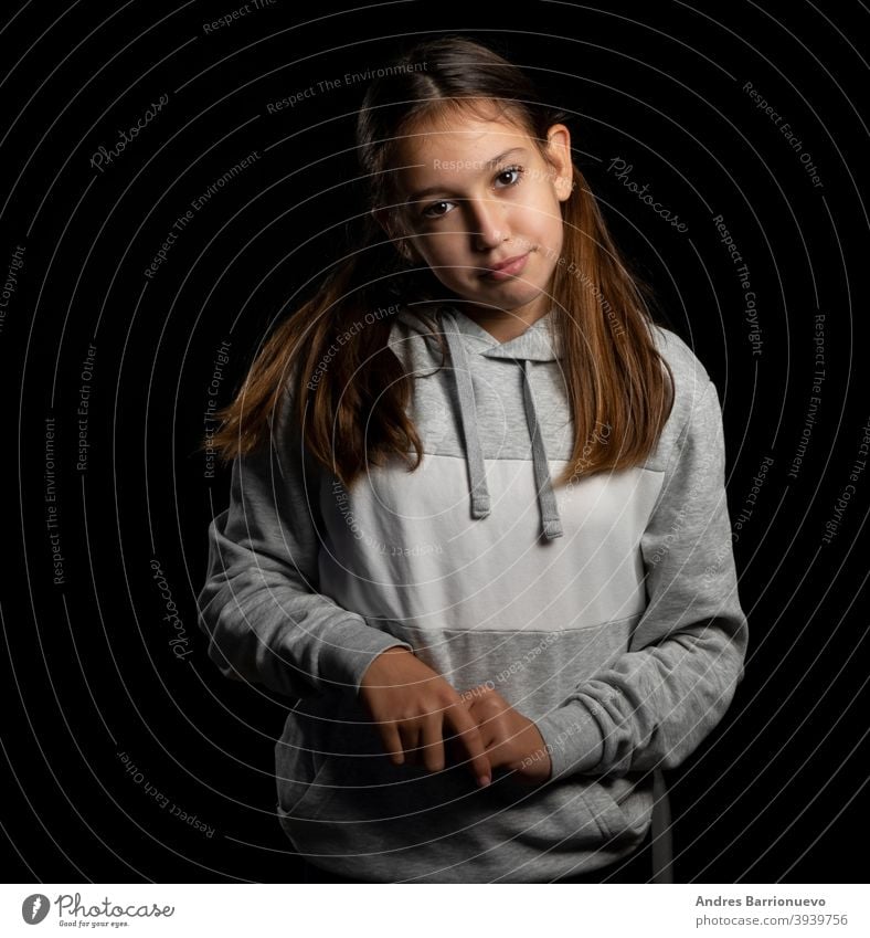 Beautiful little girl in a gray sweatshirt and with two pigtails looking up with funny attitude on a black background daughter joy positive cute people face