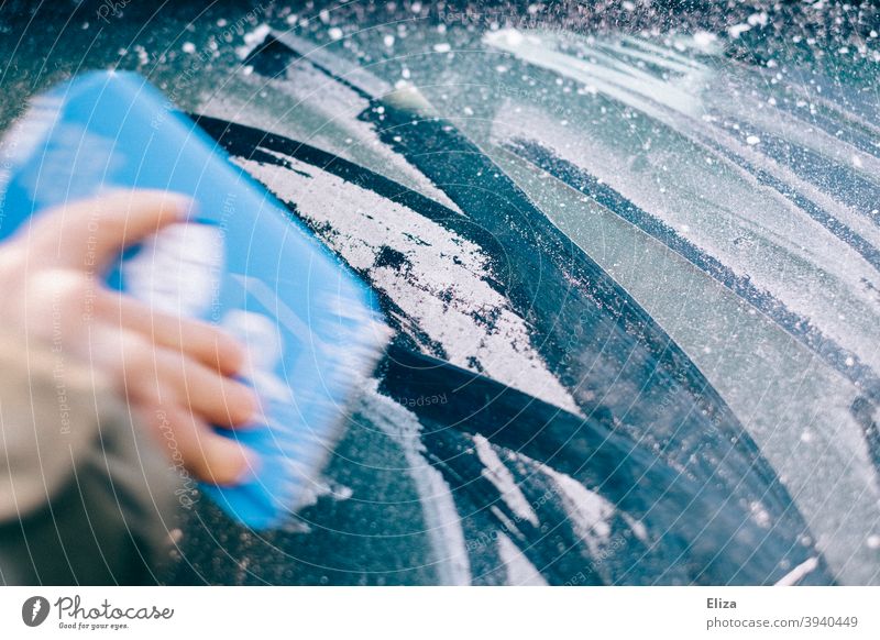 Hand scrapes the icy car window free in winter with an ice scraper Car window Frost Ice Winter Free Scratch Slice Frozen iced Car Window Windscreen Blue Cold