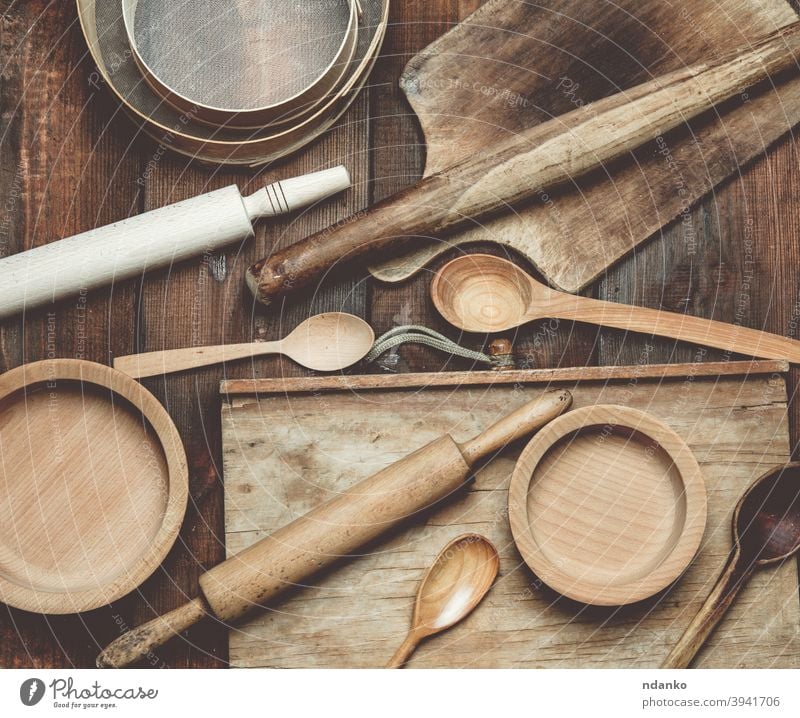 wooden kitchen vintage items: sieve, rolling pin, empty spoons and round plates on brown wooden table menu above backdrop background board cooking cuisine
