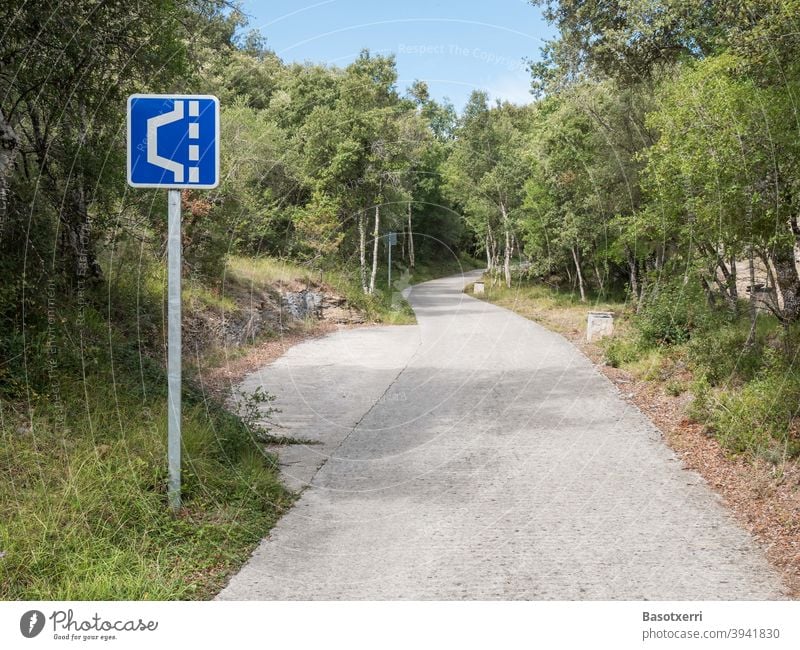 Swerve on a narrow road in the forest sign Road sign Sign symbol Blue White Street Narrow Site Country road Forest mountain pass road Summer Transport Spain
