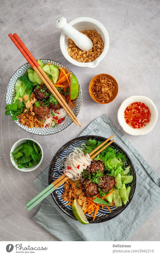 Top down view of two Vietnamese vermicelli bowls, Bun Cha, with fresh vegetarian ingredients, dipping sauce, peanuts and fried onions asia asian background
