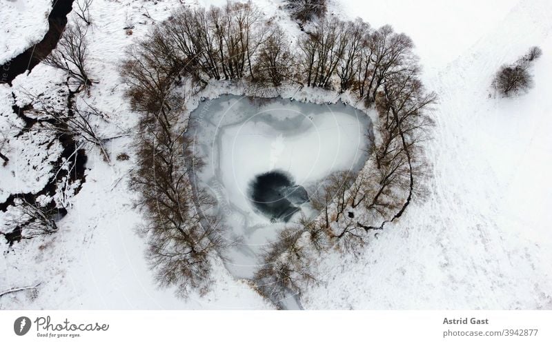 Aerial view from drone of frozen lake in heart shape or triangle shape in winter Aerial photograph drone photo Lake Body of water Frozen Ice Winter Snow