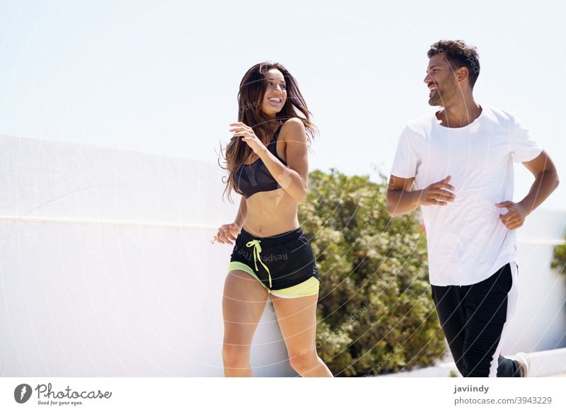 Young beautiful couple training together running outdoors - a