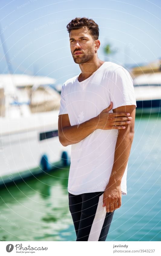 Fitness model in sportswear outfit posing on waterfront harbour. man fitness activity young leisure caucasian lifestyle person outdoor sporty white copy space