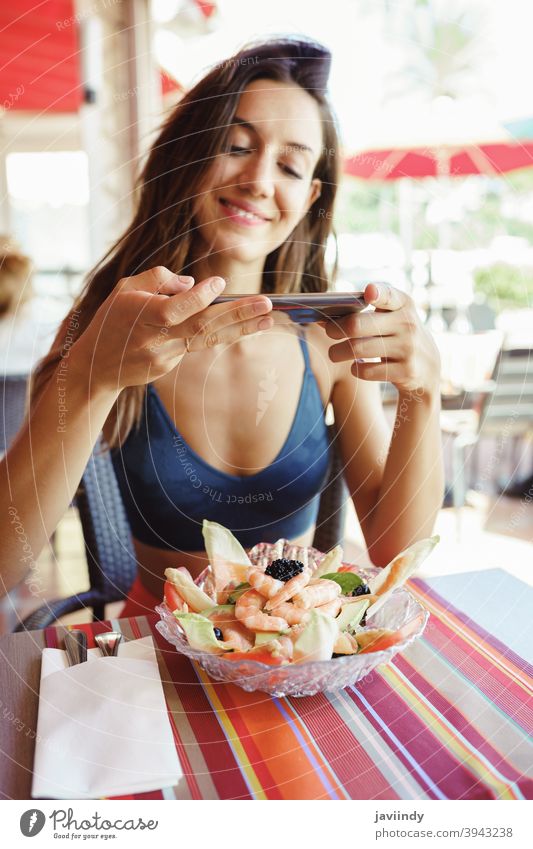 Young woman photographing her salad with a smartphone while sitting in a restaurant food healthy mobile table lunch young photography camera lifestyle female