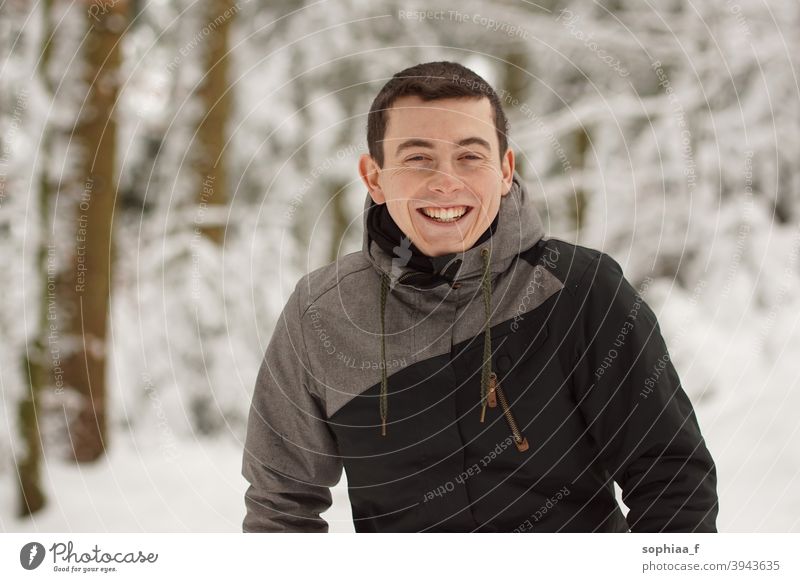 Winter - happy young man having fun in snow and laughing, smiling into the camera portrait winter teenager happiness joy boy guy cold skiing outdoor snowy male