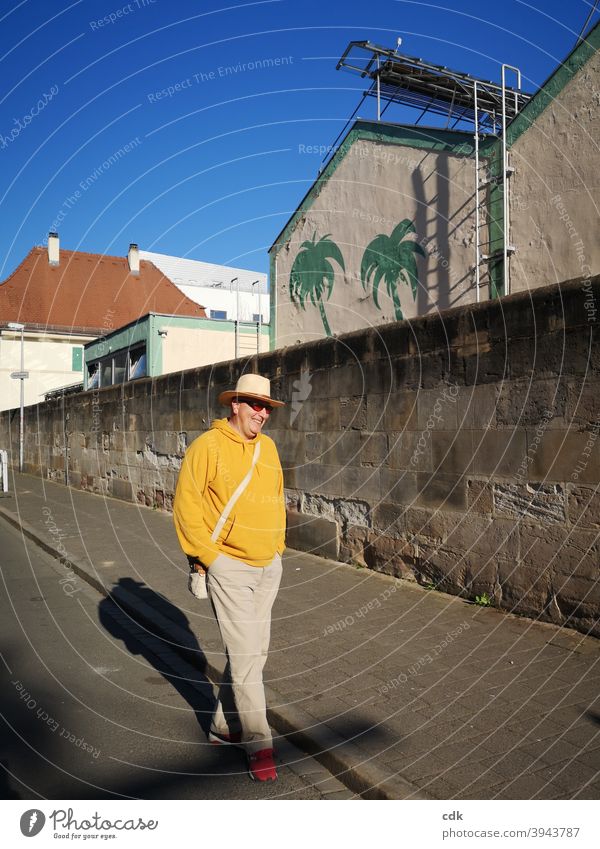 masculine and urban | calm and relaxed Man Street To go for a walk stroll by oneself Smiling free time Sun sunny Yellow Hat Wall (barrier) Town City walk Shadow