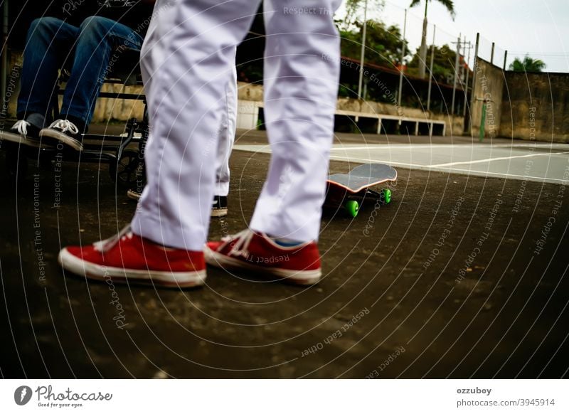 a boy in wheelchair with skateboarder friends playing in tennis court leisure life balance subculture background copy space real people equipment deck joy