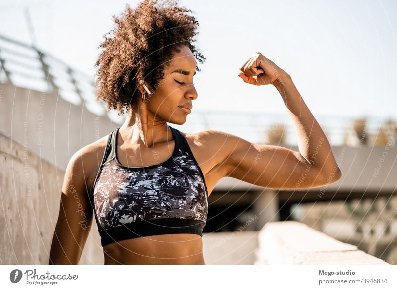 Afro athlete woman flexing and showing muscles. Stock Photo by megostudio