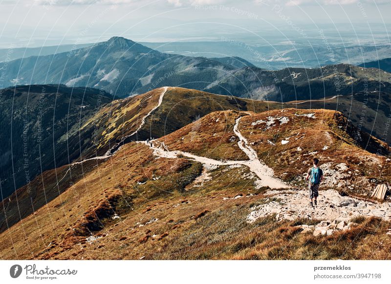 Young man with backpack hiking in a mountains, actively spending summer vacation activity adventure freedom healthy joy leisure nature park recreation spring