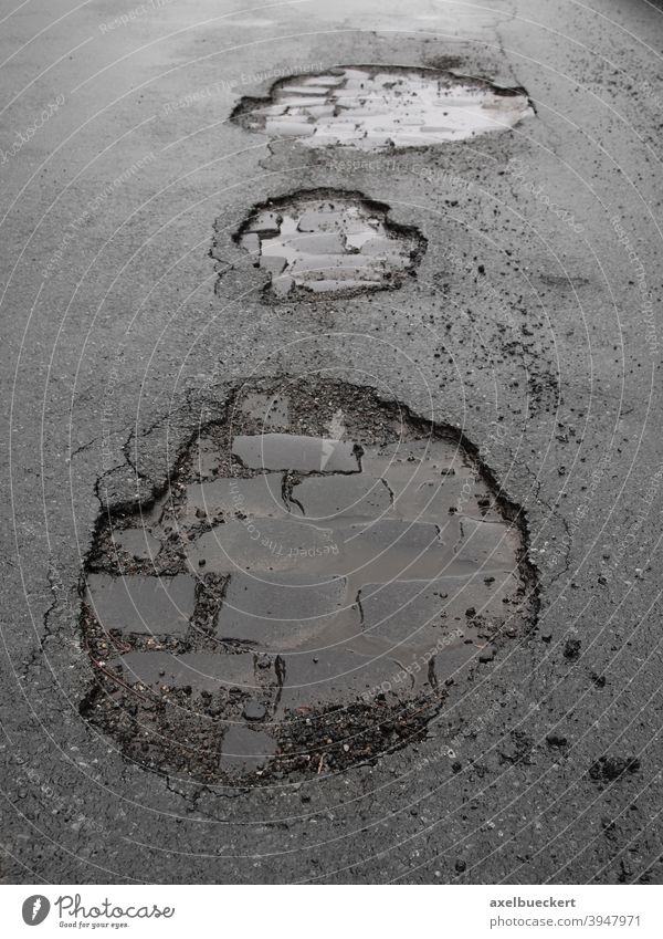potholes road damage asphalt street traffic tarmac city urban broken cracked cobblestones wet rain winter danger hazard damaged infrastructure transportation