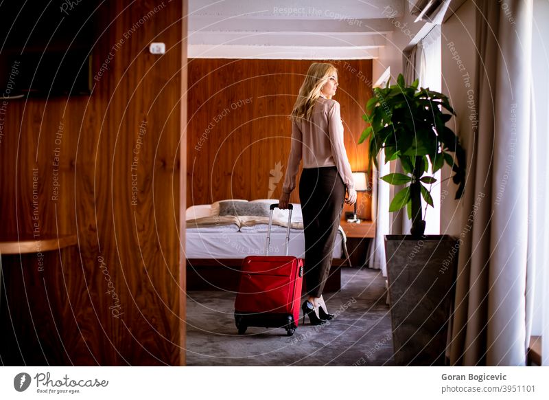 Young businesswoman arrives in a hotel room with red suitcase adult arrival bag bed bedroom caucasian charming elegance female holiday home indoor interior