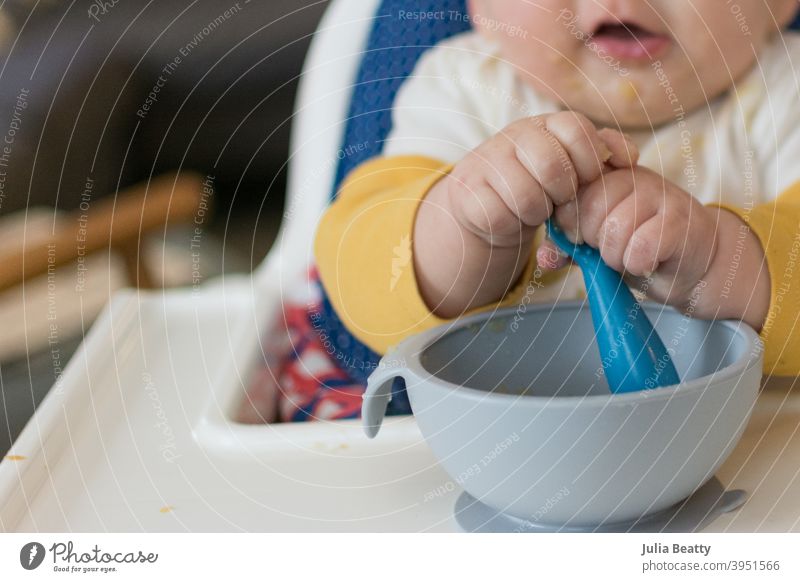 6 month old baby in high chair grasping spoon with two hands while self feeding baby led weaning first foods apple apple sauce finger foods hold child eating